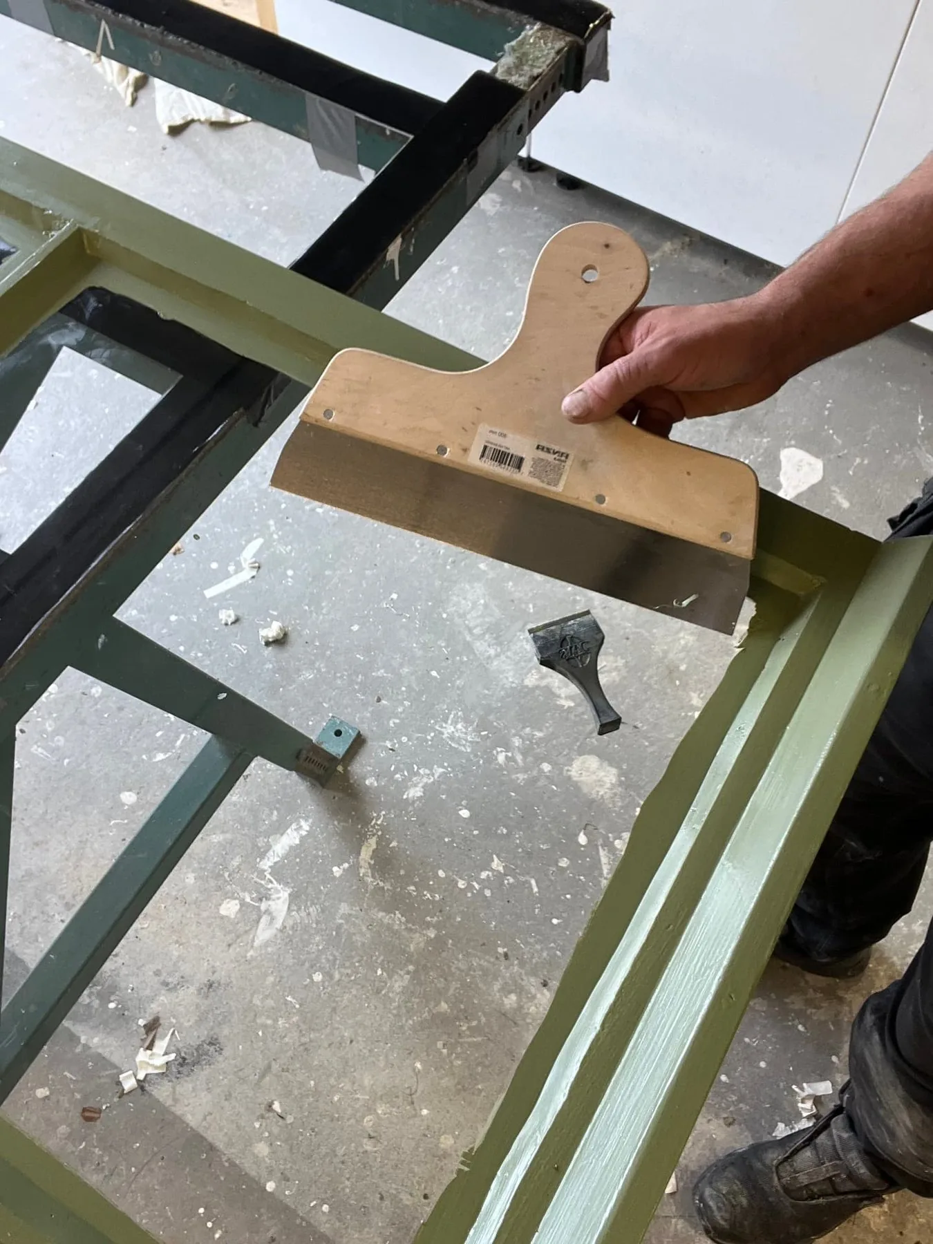 Renskärning av färgkanten på glaset med spackelspade efter målning