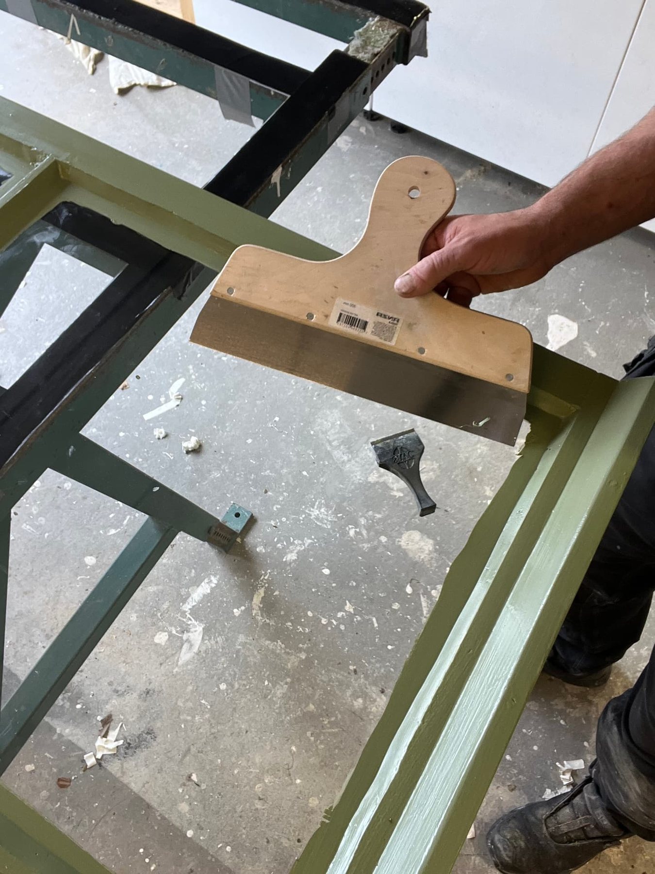Renskärning av färgkanten på glaset med spackelspade efter målning